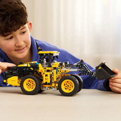 Pala gommata Volvo L120 Electric fotografia bambino con set lego tra le mani